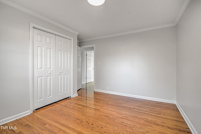 unfurnished bedroom featuring ornamental molding, light wood-type flooring, and a closet