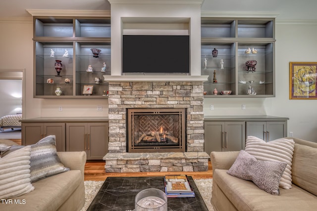 living room with a stone fireplace, light wood-type flooring, and ornamental molding