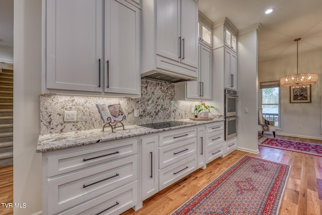 kitchen featuring double oven, black electric stovetop, light hardwood / wood-style flooring, and white cabinetry