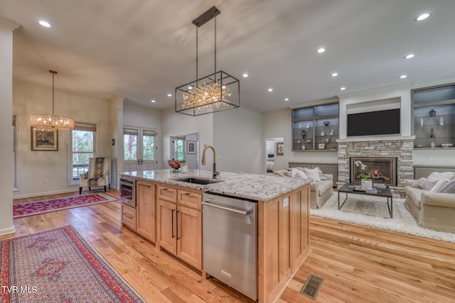 kitchen featuring light brown cabinetry, light hardwood / wood-style floors, sink, and stainless steel dishwasher