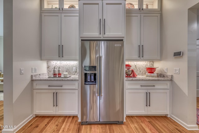 kitchen with tasteful backsplash, stainless steel refrigerator with ice dispenser, and light hardwood / wood-style flooring