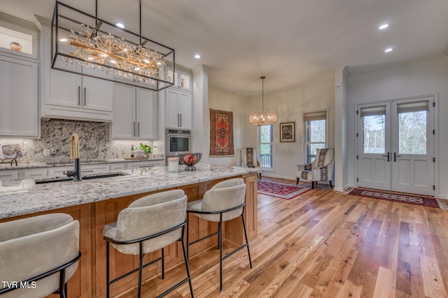 kitchen with light stone counters, white cabinets, light hardwood / wood-style flooring, and a healthy amount of sunlight