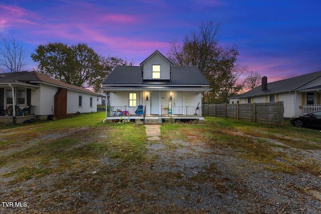 back house at dusk featuring a porch