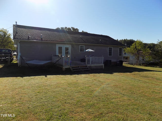 rear view of house featuring a yard, a wooden deck, central air condition unit, and french doors