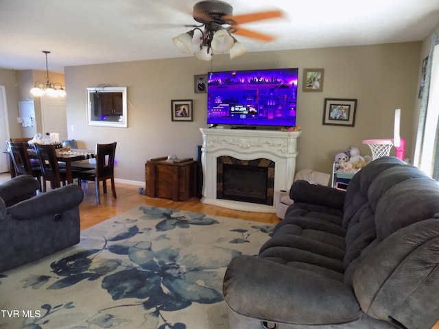 living room with ceiling fan with notable chandelier and light wood-type flooring