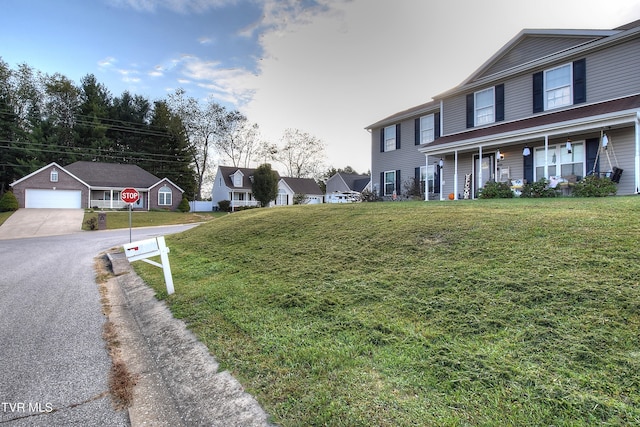 view of front of home featuring a garage, an outdoor structure, a front lawn, and covered porch