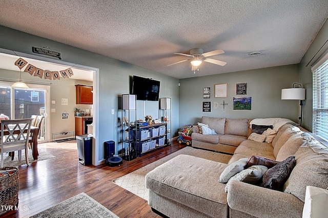 living room featuring ceiling fan, a textured ceiling, baseboard heating, and dark hardwood / wood-style floors