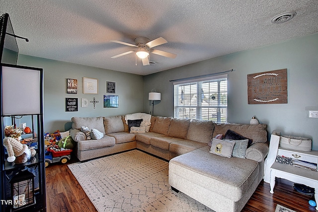 living room with dark hardwood / wood-style flooring, ceiling fan, and a textured ceiling