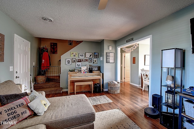 living room featuring hardwood / wood-style flooring, ceiling fan, and a textured ceiling