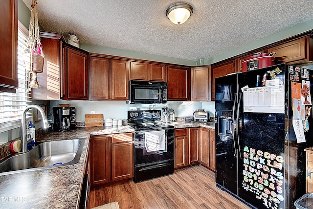 kitchen featuring a textured ceiling, light wood-type flooring, sink, and black appliances