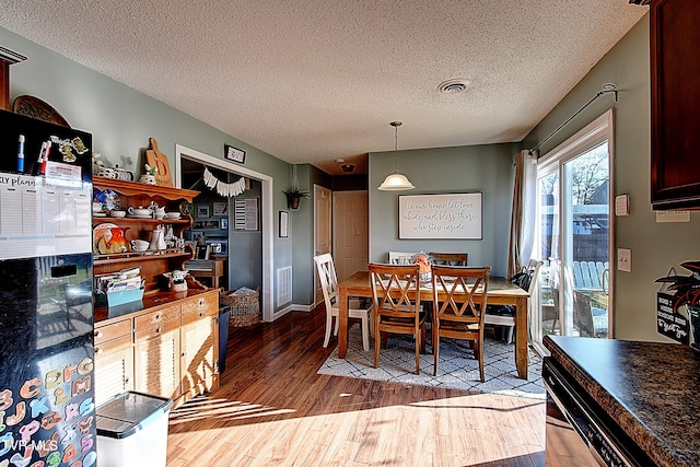 dining area featuring wood-type flooring and a textured ceiling