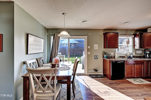 dining space featuring a healthy amount of sunlight, dark wood-type flooring, sink, and a textured ceiling