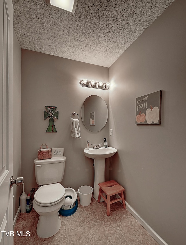 bathroom with sink, tile patterned flooring, toilet, and a textured ceiling