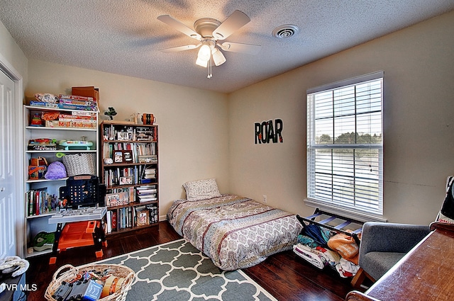 bedroom with ceiling fan, a textured ceiling, and dark wood-type flooring