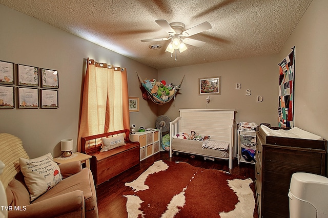 bedroom featuring ceiling fan, dark wood-type flooring, and a textured ceiling