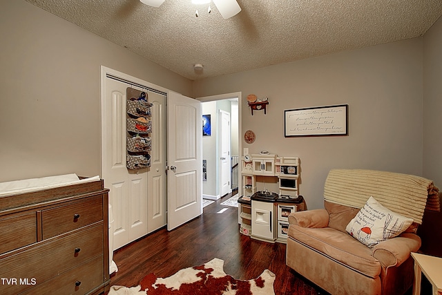 sitting room with ceiling fan, a textured ceiling, and dark wood-type flooring