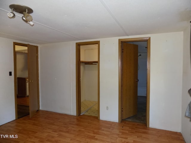 unfurnished bedroom featuring a closet, a walk in closet, and light hardwood / wood-style flooring