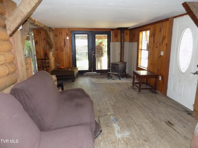 living room featuring wood-type flooring, wooden walls, and a wood stove