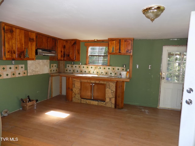 kitchen with light wood-type flooring, backsplash, sink, and a fireplace