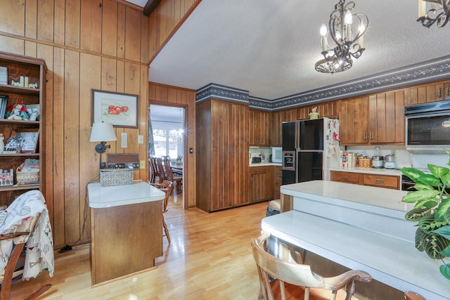 kitchen with wood walls, light hardwood / wood-style floors, a kitchen island, black fridge, and hanging light fixtures