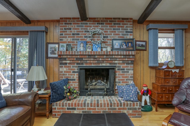 living room with plenty of natural light, beamed ceiling, a brick fireplace, and wooden walls