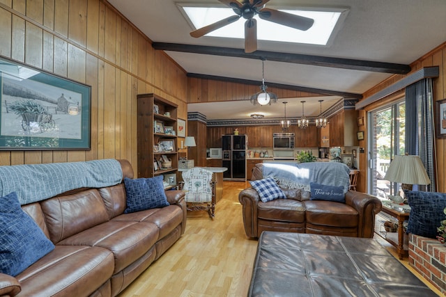 living room with ceiling fan with notable chandelier, light wood-type flooring, wooden walls, and lofted ceiling with beams