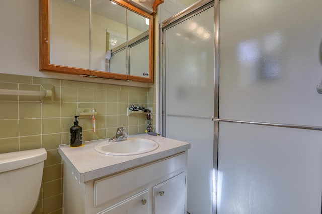 bathroom featuring decorative backsplash, vanity, a shower with door, and toilet