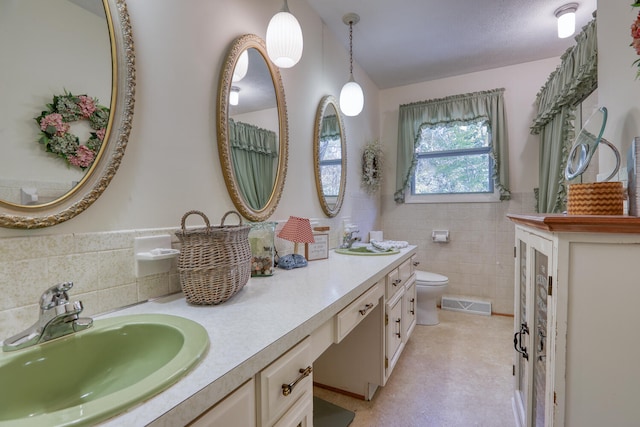 bathroom with vanity, tile walls, and toilet