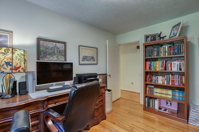 office area with light hardwood / wood-style floors and a textured ceiling