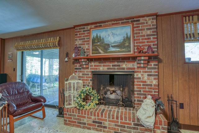 living room with ornamental molding, a brick fireplace, wood walls, and a textured ceiling