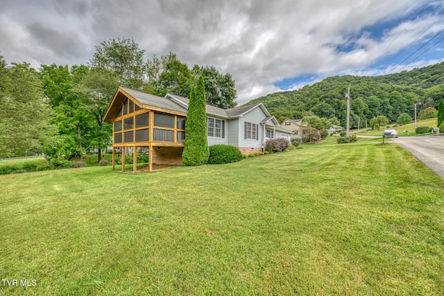 exterior space featuring a mountain view, a sunroom, and a lawn