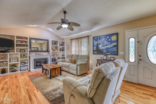 living room with vaulted ceiling, a textured ceiling, light hardwood / wood-style floors, and ceiling fan