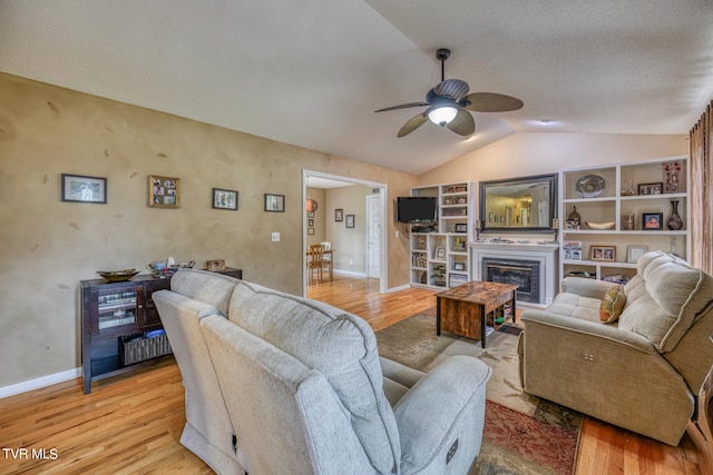 living room featuring ceiling fan, built in features, lofted ceiling, and light hardwood / wood-style flooring