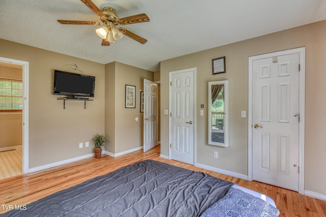 bedroom with ceiling fan, hardwood / wood-style flooring, a textured ceiling, and multiple windows