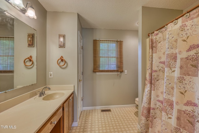 bathroom featuring vanity, toilet, and a textured ceiling