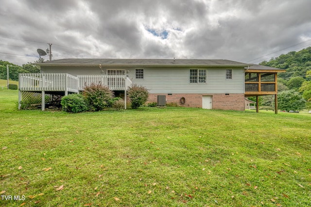 rear view of property featuring a yard, a wooden deck, and central AC unit