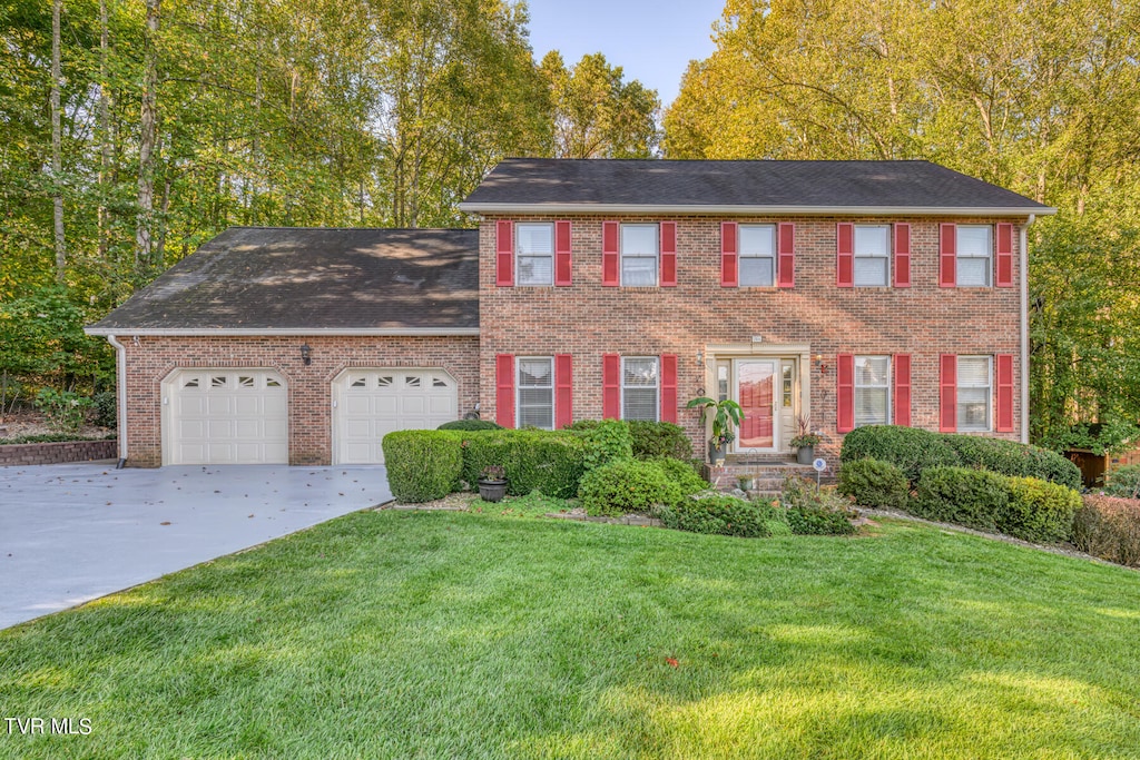 colonial inspired home with a garage and a front yard