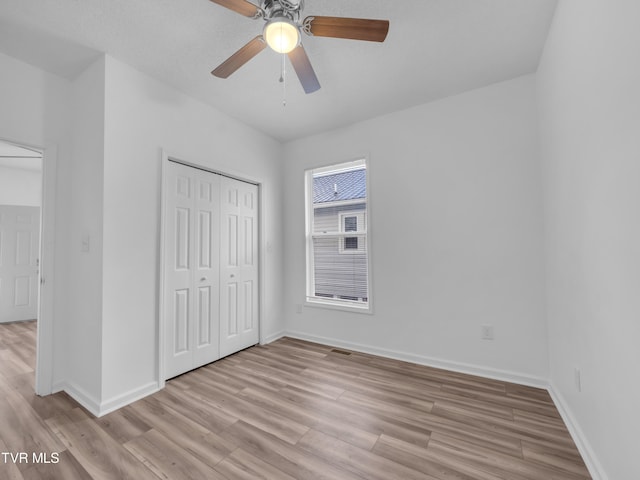 unfurnished bedroom featuring a closet, light hardwood / wood-style floors, and ceiling fan