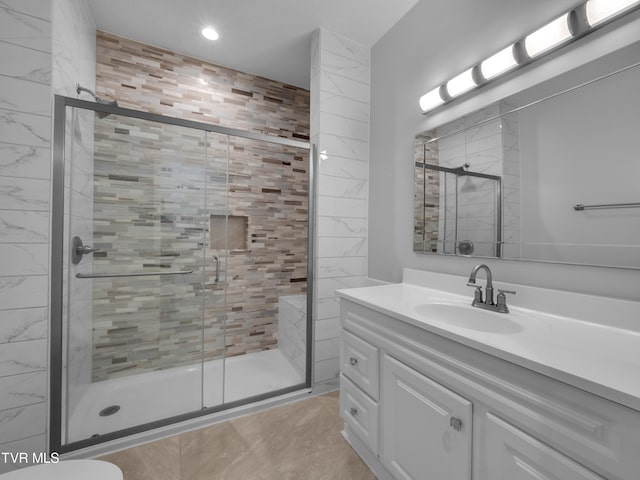 bathroom featuring a shower with door and vanity