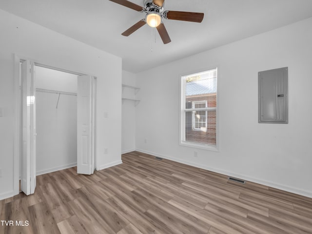 unfurnished bedroom featuring a closet, electric panel, light wood-type flooring, and ceiling fan