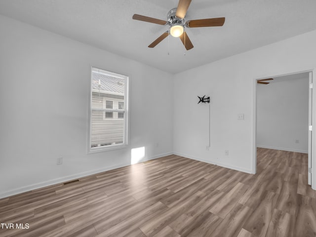empty room with ceiling fan, a textured ceiling, and light hardwood / wood-style flooring