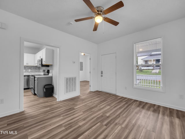 unfurnished living room with light hardwood / wood-style flooring, electric panel, and ceiling fan
