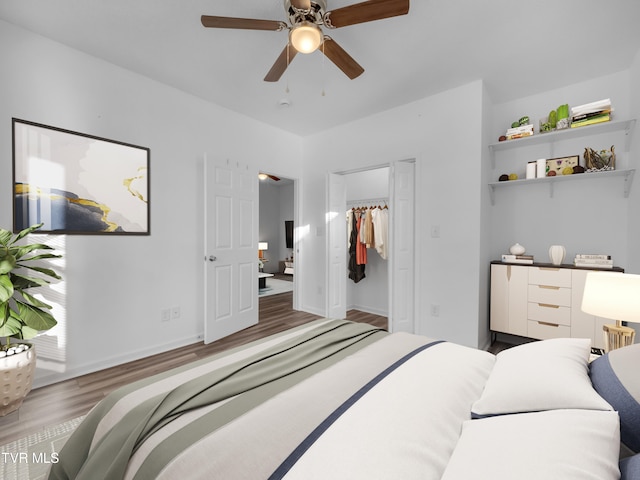 bedroom with a closet, a spacious closet, wood-type flooring, and ceiling fan