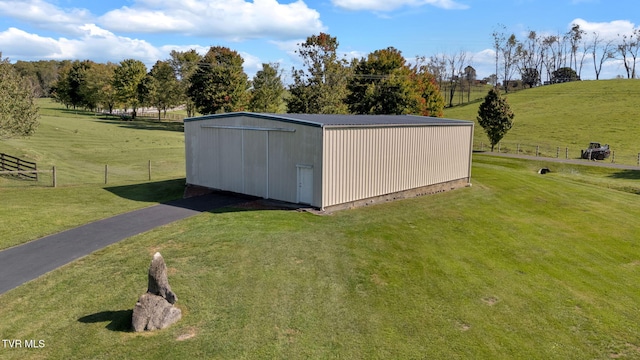 view of outbuilding featuring a rural view and a lawn