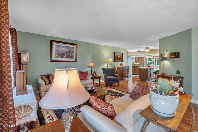 living room featuring ceiling fan, hardwood / wood-style floors, and a textured ceiling