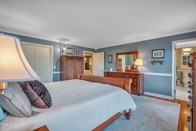 bedroom with connected bathroom, a closet, hardwood / wood-style floors, and ornamental molding