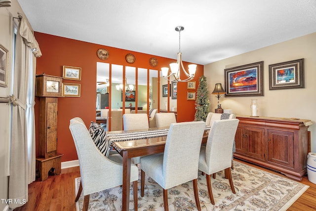 dining area featuring light wood-type flooring and an inviting chandelier