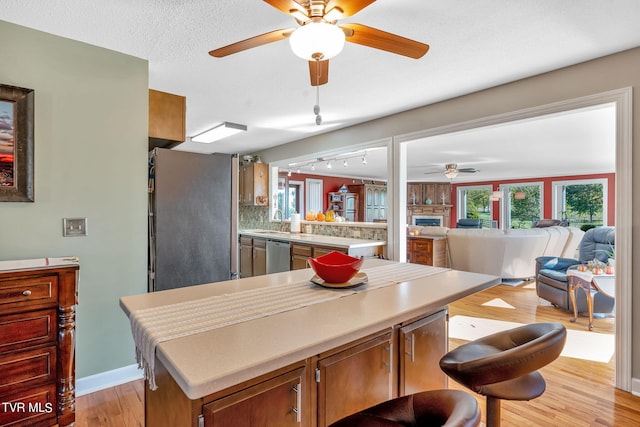 dining room featuring ceiling fan, sink, a textured ceiling, track lighting, and light hardwood / wood-style floors