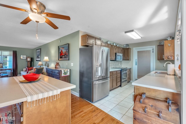 kitchen with ceiling fan, decorative backsplash, sink, light hardwood / wood-style flooring, and appliances with stainless steel finishes