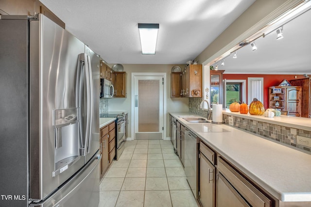 kitchen with stainless steel appliances, backsplash, sink, and rail lighting